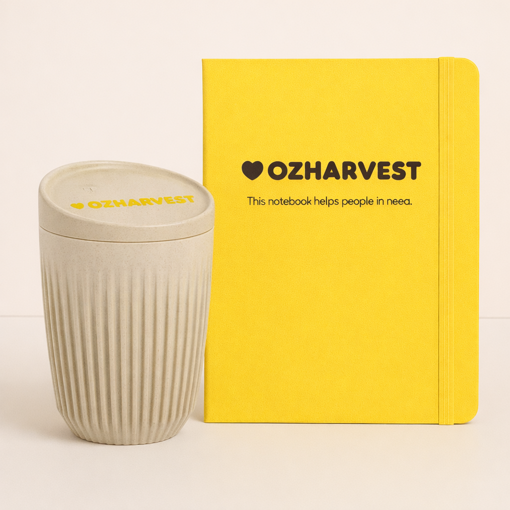 Yellow notebook and beige cup with 'OzHarvest' branding on a light background