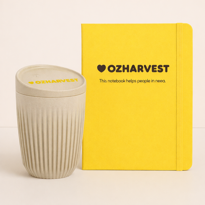 Yellow notebook and beige cup with 'OzHarvest' branding on a light background