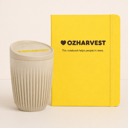 Yellow notebook and beige cup with 'OzHarvest' branding on a light background