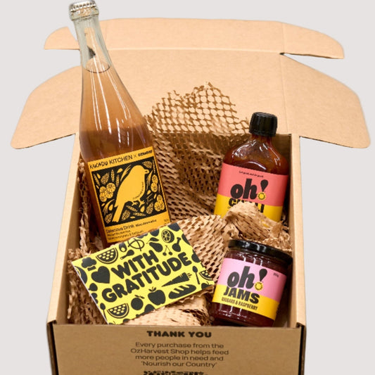 Gift basket with bottles and a jar in a cardboard box, featuring visible branding.